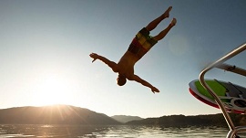 Homem mergulhando no mar a partir de um barca