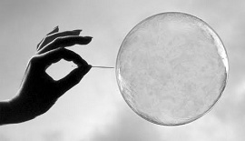 Mão com um alfinete tenta estourar uma bolha